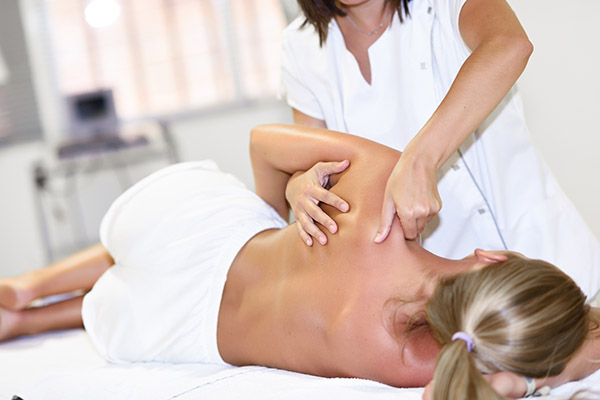 Professional female physiotherapist giving shoulder massage to b Professional female physiotherapist giving shoulder massage to b